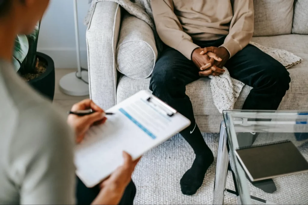 man-sitting-on-couch-during-1-on-1-therapy | Tree House Recovery Colorado Man sitting on a couch talking to a therapist during 1 on 1 therapy